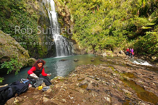 Trampers cooking lunch at Kitekite waterfall (Kitakita) on Glen Esk stream and the Hillary Trail track near Piha Beach. Waitakere Ranges Regional Park, Waitakere Ranges, Auckland, Waitakere City District, Auckland Region, New Zealand (NZ)