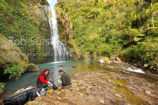 Trampers having lunch and brew at Kitekite waterfall (Kitakita) on Glen Esk stream and the Hillary Trail track near Piha Beach. Waitakere Ranges Regional Park, Waitakere Ranges, Auckland, Waitakere City District, Auckland Region, New Zealand (NZ)