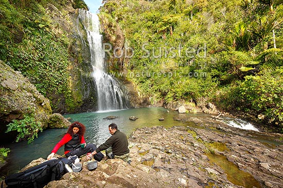 Trampers having lunch and brew at Kitekite waterfall (Kitakita) on Glen Esk stream and the Hillary Trail track near Piha Beach. Waitakere Ranges Regional Park, Waitakere Ranges, Auckland, Waitakere City District, Auckland Region, New Zealand (NZ)