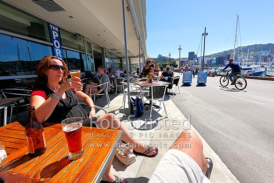 Wellington City waterfront with café diners enjoying meals and drinks near Chaffers Marina on a summer day. City skyline and te Papa Museum behind, Wellington, Wellington City District, Wellington Region, New Zealand (NZ)