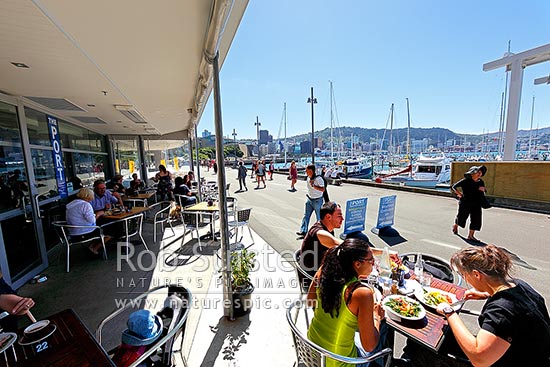 Wellington City waterfront with café diners enjoying meals and drinks near Chaffers Marina on a summer day. City skyline and te Papa Museum behind, Wellington, Wellington City District, Wellington Region, New Zealand (NZ)