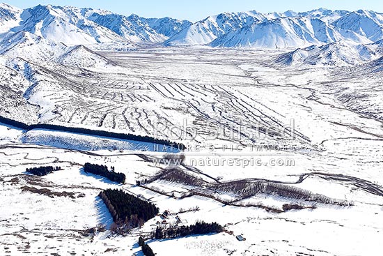 Tarndale station complex during winter snow with Sedgemere tarns, Wairau River valley, Turk and Stafford Ridges, and windrowed wilding pines beyond. Aerial, Molesworth Station, Marlborough District, Marlborough Region, New Zealand (NZ)