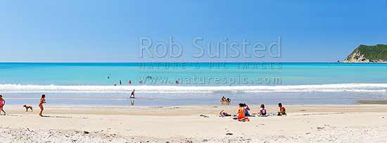 Families enjoying the summer on Waipiro Bay beach with azure blue water. Swimming, digging, sunbathing, kayaking and wave skis in surf. Panorama, Waipiro Bay, East Coast, Gisborne District, Gisborne Region, New Zealand (NZ)