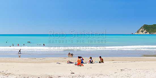 Families enjoying the summer on Waipiro Bay beach with azure blue water. Swimming, digging, sunbathing, kayaking and wave skis in surf. Panorama, Waipiro Bay, East Coast, Gisborne District, Gisborne Region, New Zealand (NZ)