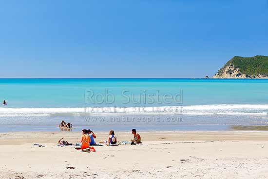 Families enjoying the summer on Waipiro Bay beach with azure blue water. Swimming, digging, sunbathing, kayaking and wave skis in surf, Waipiro Bay, East Coast, Gisborne District, Gisborne Region, New Zealand (NZ)