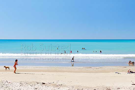 Families enjoying the summer on Waipiro Bay beach with azure blue water. Swimming, digging, sunbathing, kayaking and wave skis in surf, Waipiro Bay, East Coast, Gisborne District, Gisborne Region, New Zealand (NZ)