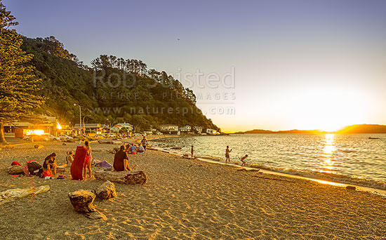 Days Bay Golden sunset looking out over Wellington Harbour. Families and friends enjoying a warm evening together swimming and socialising. Panorama, Days Bay, Hutt City District, Wellington Region, New Zealand (NZ)