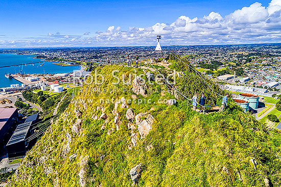 Paritutu Rock summit trig and lookout with visitors (154m) above New Plymouth city and suburbs. Aerial view, New Plymouth, New Plymouth District, Taranaki Region, New Zealand (NZ)