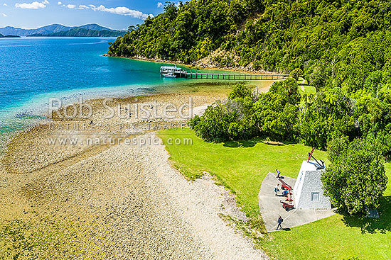 Ship Cove (Meretoto) with people enjoying Captain Cook's Monument. Outer Queen Charlotte Sound. Start of the Queen Charlotte Walking Track. Aerial view, Marlborough Sounds, Marlborough District, Marlborough Region, New Zealand (NZ)